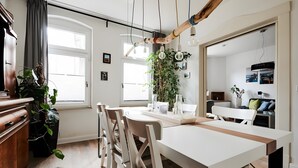 A modern kitchen with a dining area, wooden beams, and hanging light fixtures. - Unique Carpenter’s Apartment with Sea View, Balcony, and Wi-Fi (Oldenburg)