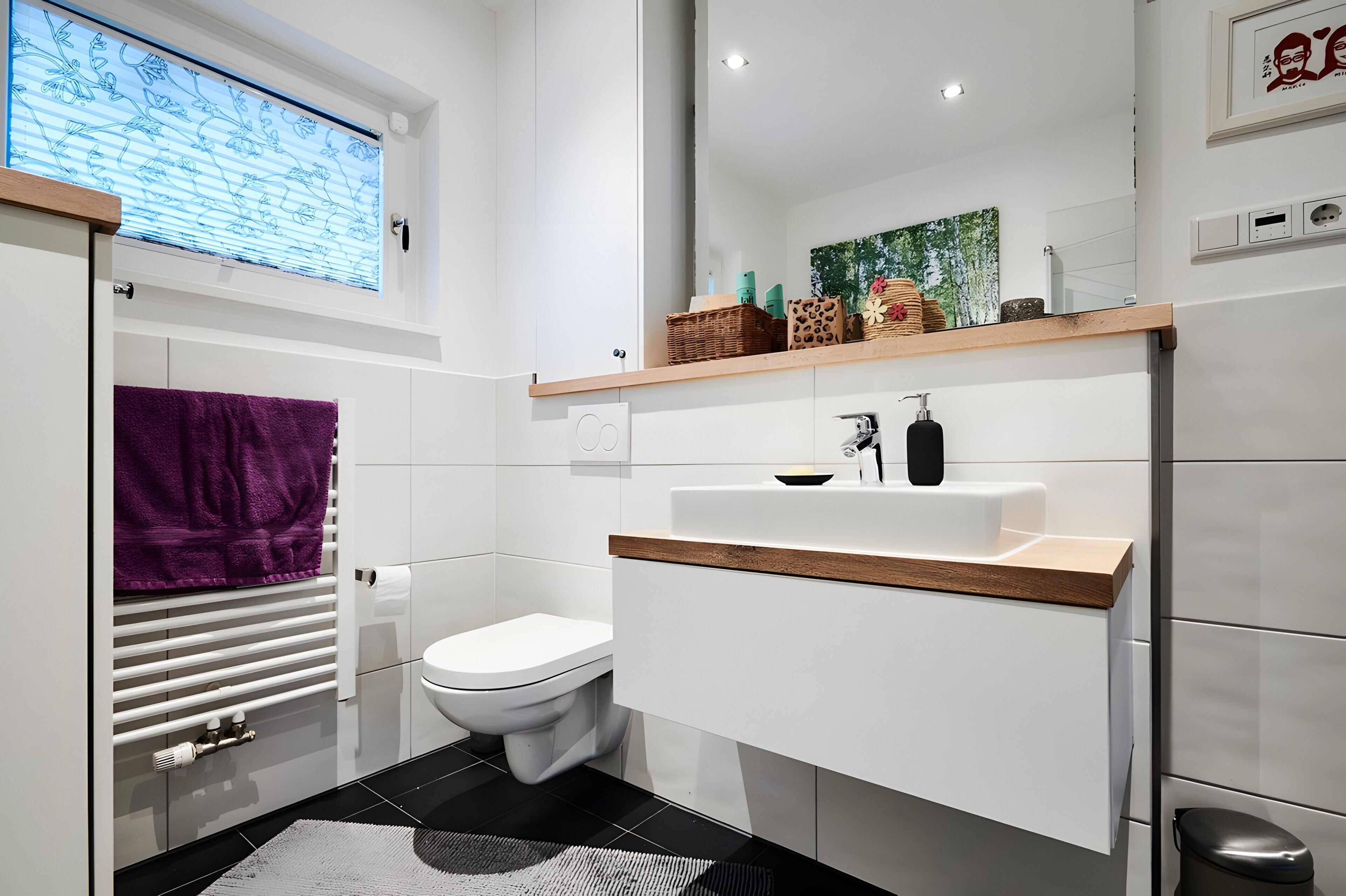 Une salle de bain moderne équipée de toilettes, d’un lavabo et d’une fenêtre avec stores.