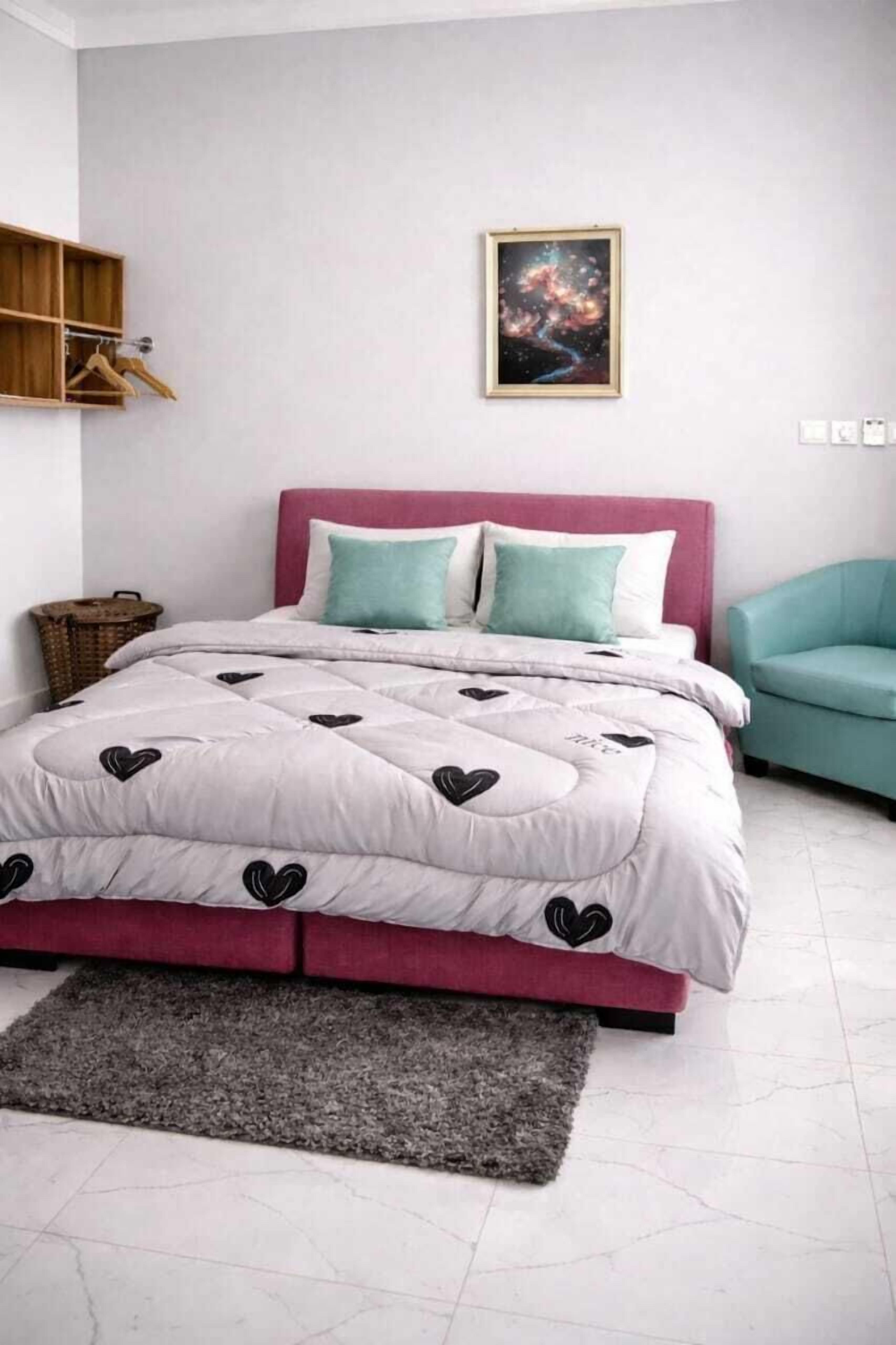 A bedroom with a bed, a headboard, a grey rug, a wall-mounted shelf, and a framed picture.