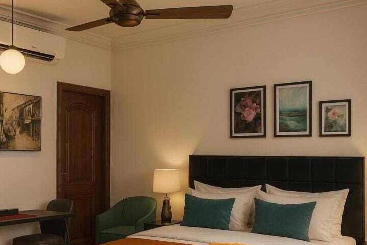 Een hotelkamer met een groot bed, een bureau, een stoel en een plafondventilator.