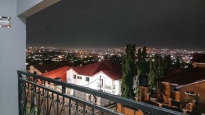 A balcony with a metal railing overlooking a cityscape at night. - Deutsch Inn Luxury Apt (Weija)