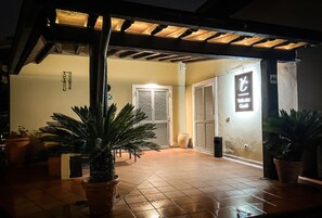 An outdoor area with a tiled floor, potted plants, and a sign indicating a restaurant. - Valle dei Casali (Rome)