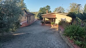 A paved courtyard with a stone floor, surrounded by buildings with tiled roofs and potted plants. - Valle dei Casali (Rome)