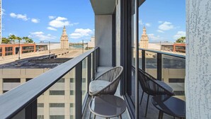 Un balcon avec deux chaises et une table, donnant sur un paysage urbain avec des immeubles et une rivière.