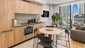 Une cuisine moderne avec des meubles en bois, un four encastré et un coin repas comprenant une table ronde et des chaises.