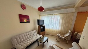Un soggiorno con un divano, un tavolino, un mobile TV, una poltrona e un quadro appeso al muro.
