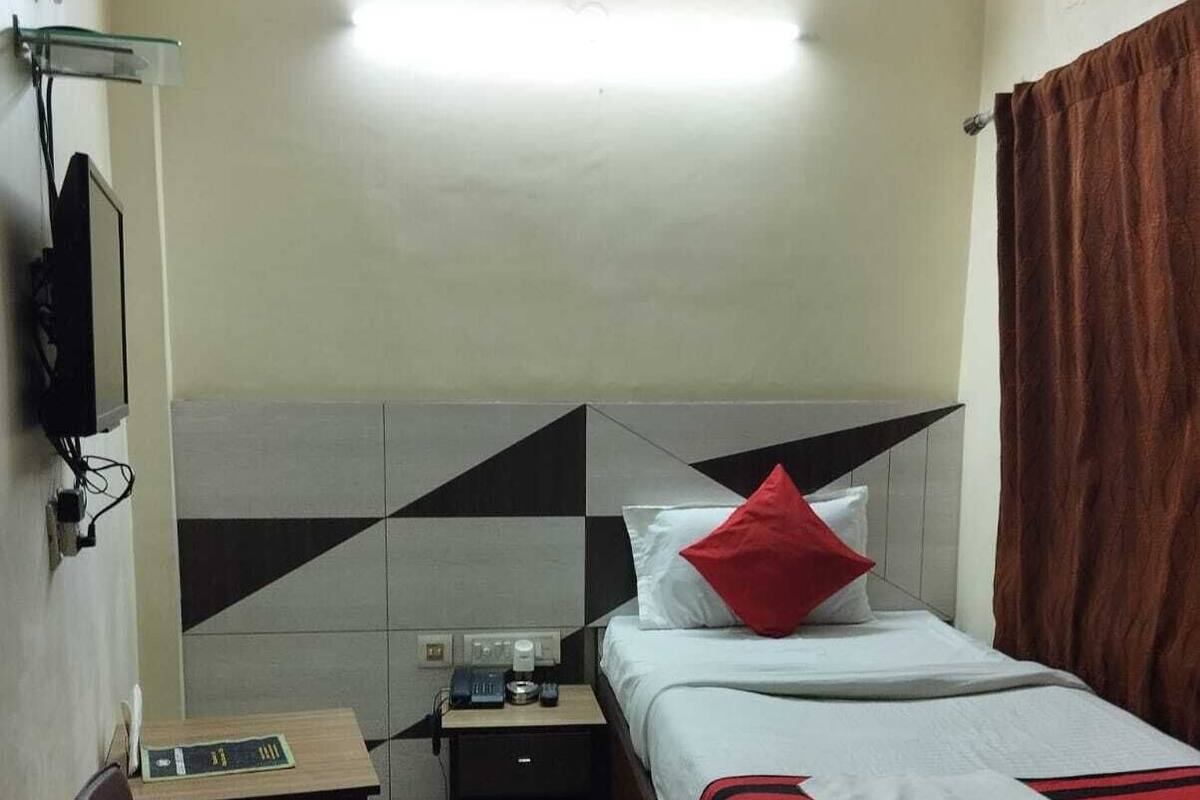A hotel room with a bed, a desk, a chair, a nightstand, and a TV.