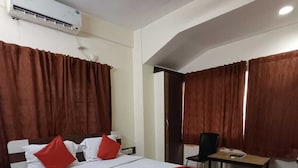 Hotellihuone, jossa on sänky, työpöytä ja ilmastointilaite.