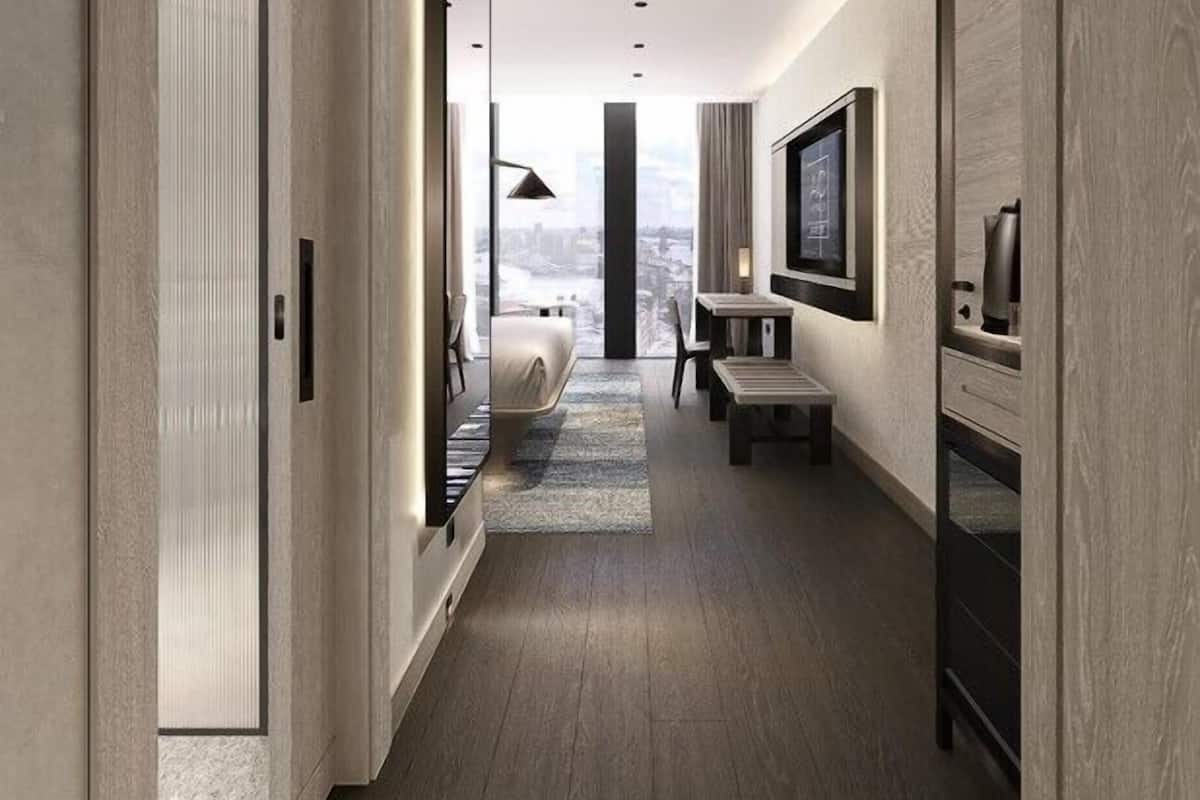 Un couloir d’hôtel moderne avec vue sur la ville, comprenant un lit, une télévision et un bureau.