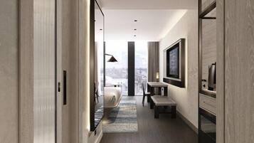 A modern hotel hallway with a view to the city, a bed, a TV, and a desk.