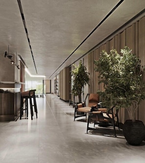 A modern interior with a long hallway, seating area with chairs, a large potted plant, and a reception desk. - ART Riverfront Hotel Tbilisi (Tbilisi)