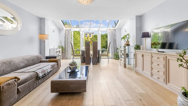 A spacious living room with a sofa, coffee table, and TV. A glass door leads to an outdoor area with a view of buildings and greenery. - 3-bed Greenhithe Retreat Garden Near Bluewater (Greenhithe)