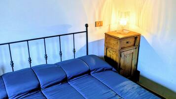 Un letto con struttura in metallo e un comodino in legno con una lampada.