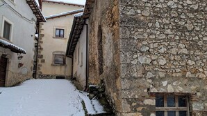 A narrow snow-covered street flanked by stone buildings with traditional architecture. - Lucoli Antico (Lucoli)
