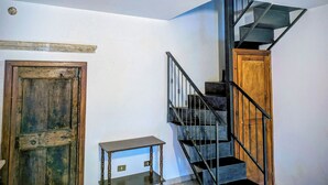 A staircase with a wooden finish and metal railings, leading to a landing with a small table and a door. - Lucoli Antico (Lucoli)