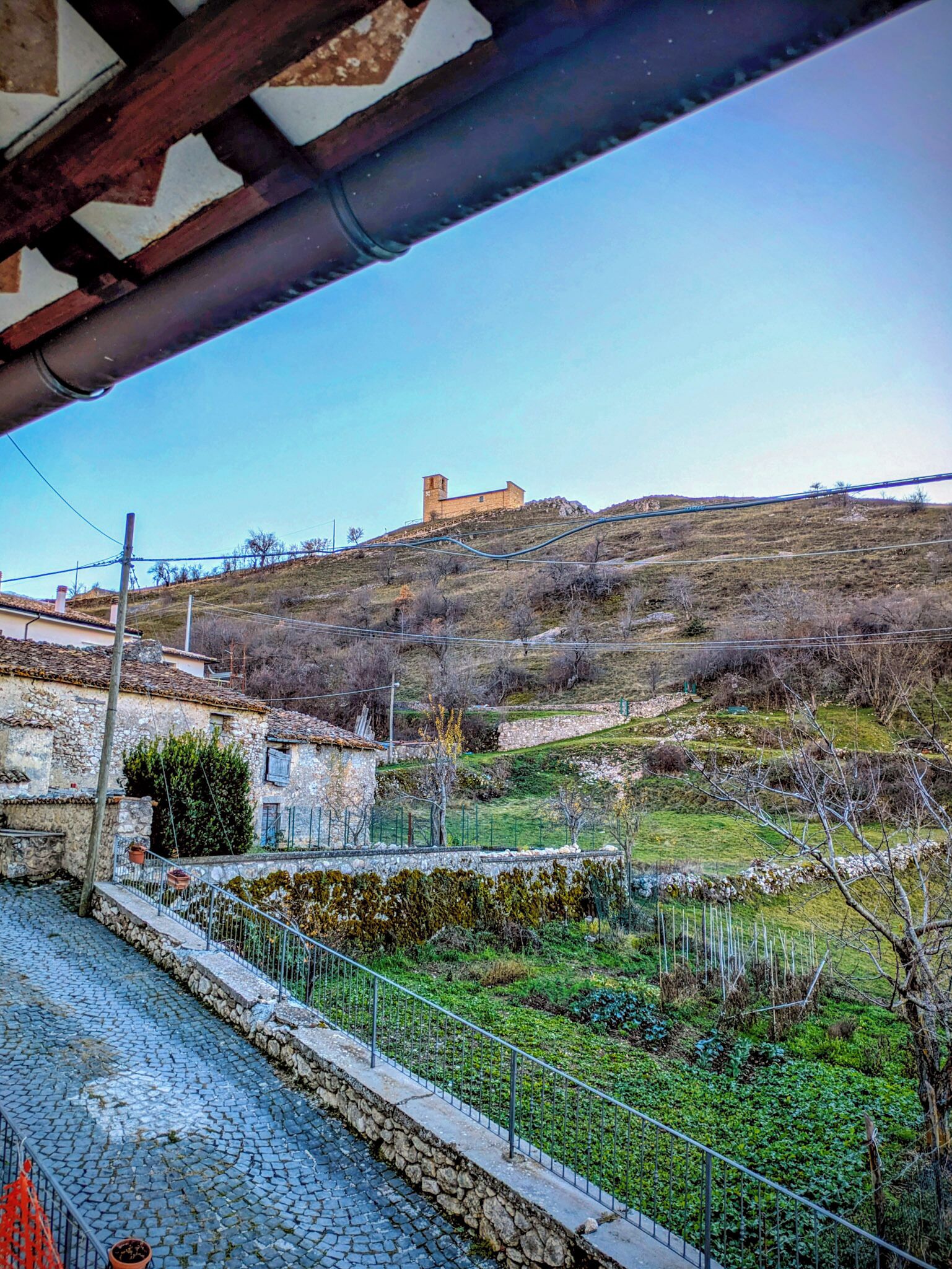 Un bâtiment en pierre situé sur une colline, sous un ciel dégagé.