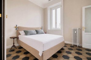 A bedroom with a bed, a bedside table, a window, and a radiator. - w Bright 2BR Near Arco Della Pace (Milan)