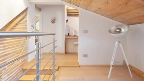 A modern interior with a wooden staircase, a white floor lamp, and a kitchen area. - Address: Calle de le Ancore, 1044 - Castello BiennaleGoogle maps ' position: https://maps.app.goo.gl/ZF2iGXAu1hQr4UdG7The apartment is located on the third floor, consisting of a bedroom, bathroom with tub, living room with sofa bed for 2 people, kitchen (Venezia)