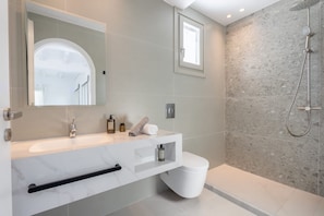 A modern bathroom with a marble sink, a toilet, a shower with a handheld showerhead, and a large mirror. - Eidolion Essence - Mykonos Villa With Private Pool (Mykonos)