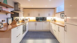 Een moderne keuken met witte kasten, een roestvrijstalen afzuigkap en een houten aanrecht.