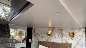 A modern reception area with a marble wall, a reception desk, and a staircase. - SHREE LODGING & BOARDING (Vasai)