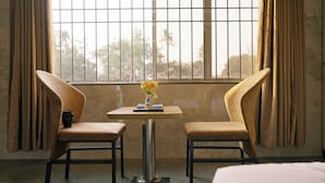 A room with two chairs, a small table, and a window with curtains. - SHREE LODGING & BOARDING (Vasai)