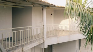 A balcony with a white railing, a tiled floor, and a door leading to an interior space. - SHREE LODGING & BOARDING (Vasai)
