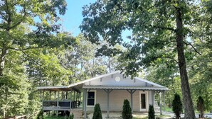 A single-story house with a porch, surrounded by trees and a fenced yard. - Kettlestone (Stanton)