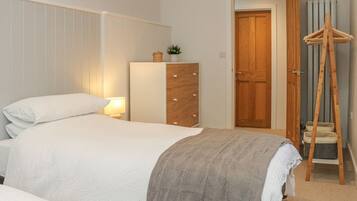 Une chambre à coucher avec un lit, une commode et une porte en bois.
