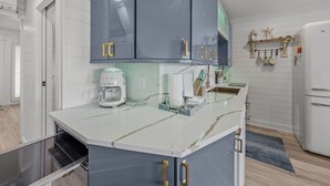 Uma cozinha com bancada de mármore branco, cafeteira e pia.