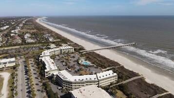 An aerial view of a coastal hotel with multiple buildings, a beach, and a pier.