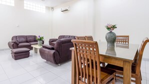 A modern living room with a sofa set, a dining table with chairs, and an air conditioning unit on the wall. - Collection O 294 Andrea Residence (Medan)