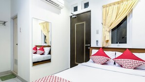 A hotel room with a bed, a mirror, a window with curtains, and a door. - Collection O 294 Andrea Residence (Medan)