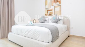 A bedroom with a bed, a nightstand, and a wall with framed artwork. - Bloomfields Modern 1Br Water's edge (Abu Dhabi)