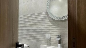 A bathroom with a modern design, featuring a large mirror, a white sink, and a toilet. - Triple Room with Garden View at Saloumy Pyramids HotelWonders (Nazlat as Sammān)