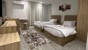 A modern hotel room with a wooden bed, a desk, and a chair. - Triple Room with Garden View at Saloumy Pyramids HotelWonders (Nazlat as Sammān)