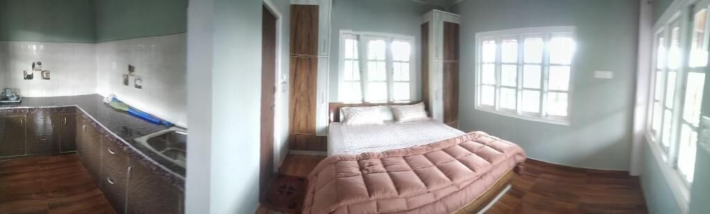 A bedroom with a bed, a window, and a bathroom with a sink and mirror.