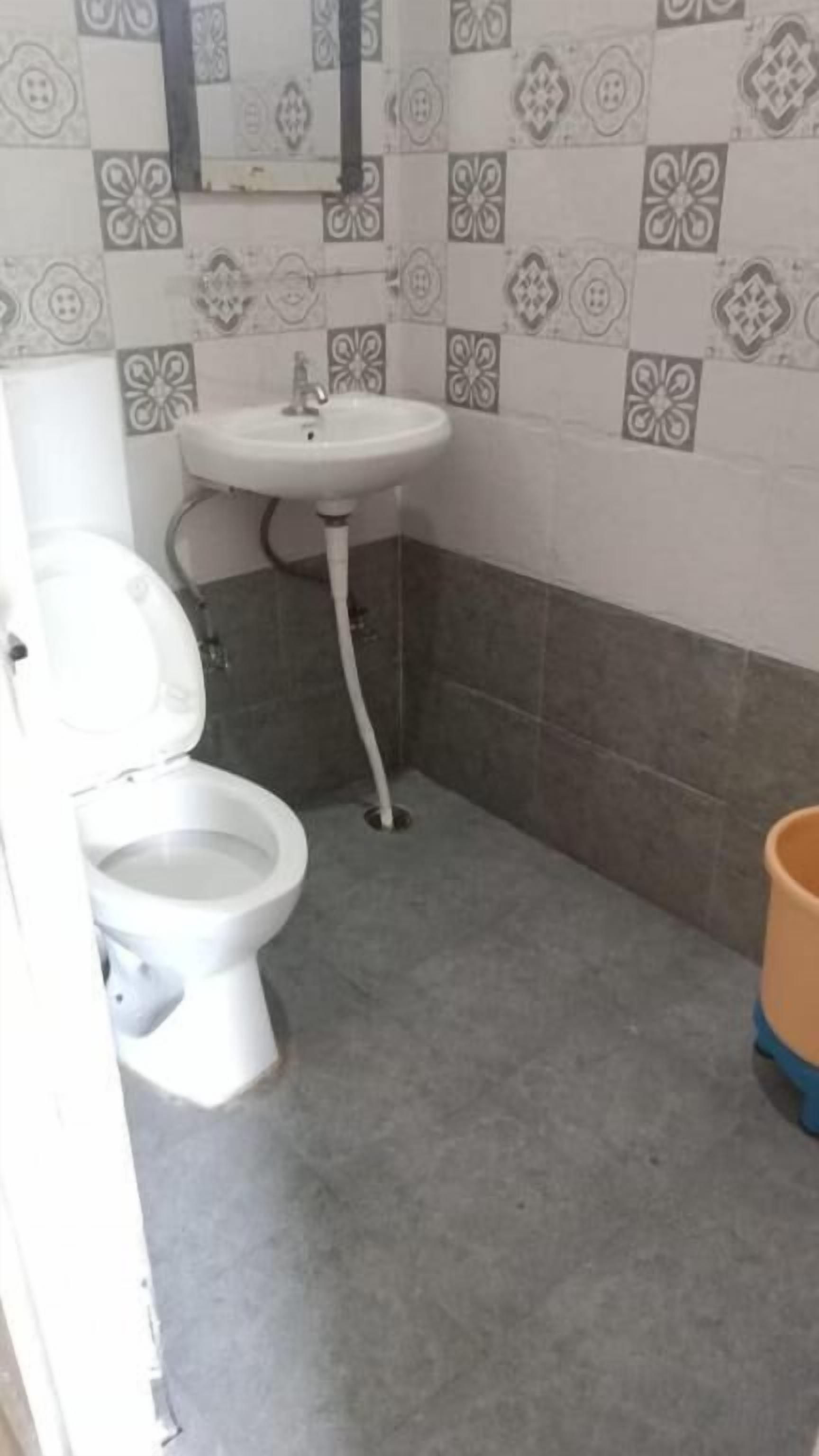 Un bagno con il water, un lavandino e pareti piastrellate.