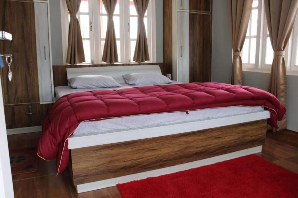 Quarto com cama, cabeceira de madeira e tapete vermelho.