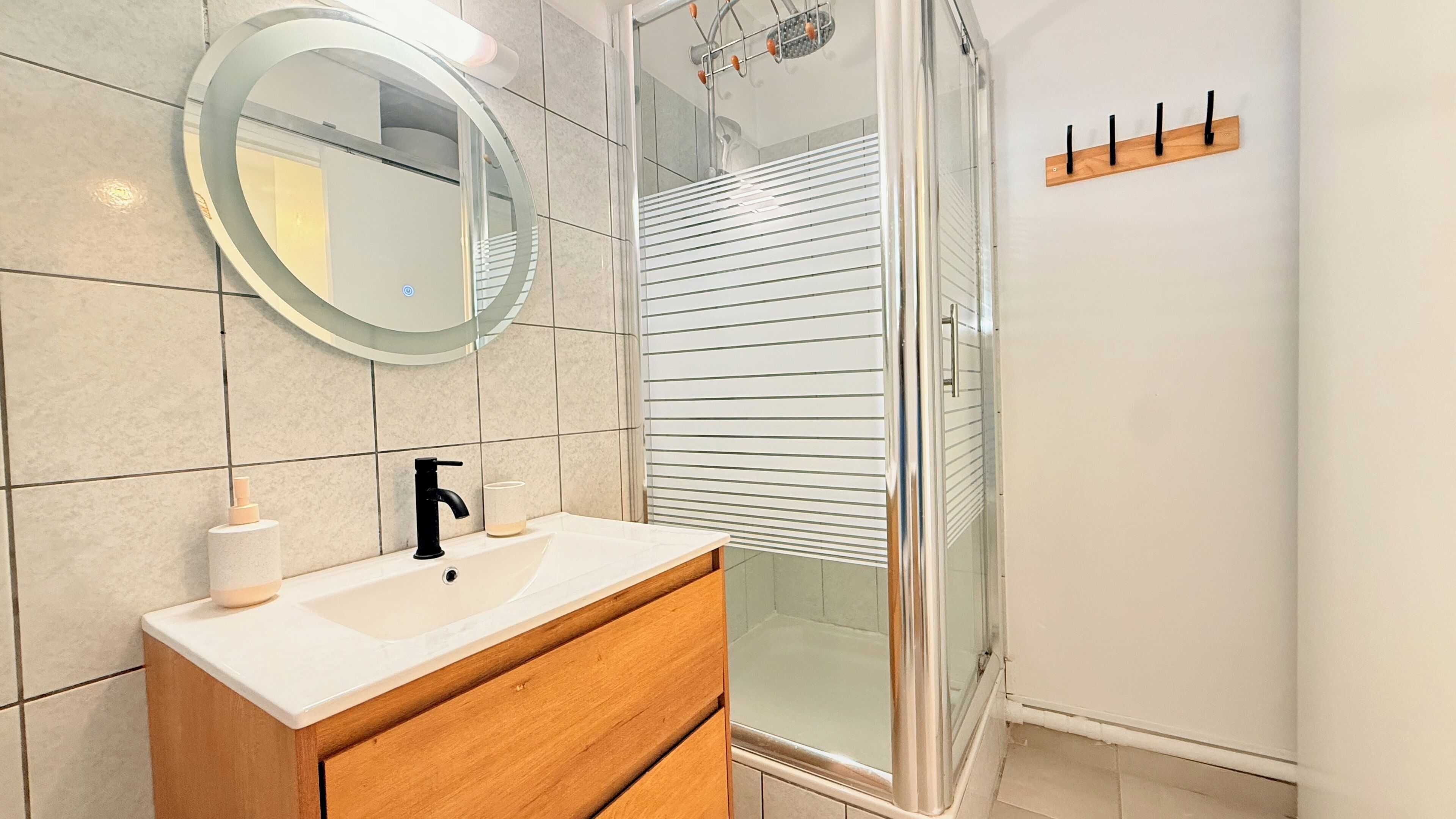 A bathroom with a white sink, a mirror, and a glass shower enclosure.