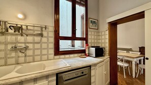 A kitchen with a dishwasher, a microwave, and a window with a view of the street. - Zanobi 75 in Firenze (Florence)