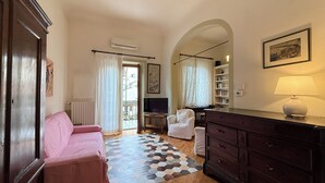 A hotel room with a pink sofa, a wooden dresser, a television, a bookshelf, and a large mirror. - Zanobi 75 in Firenze (Florence)