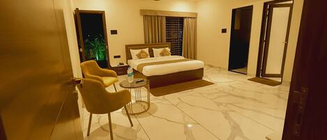 A hotel room with a bed, a chair, a small table, and a mirror.