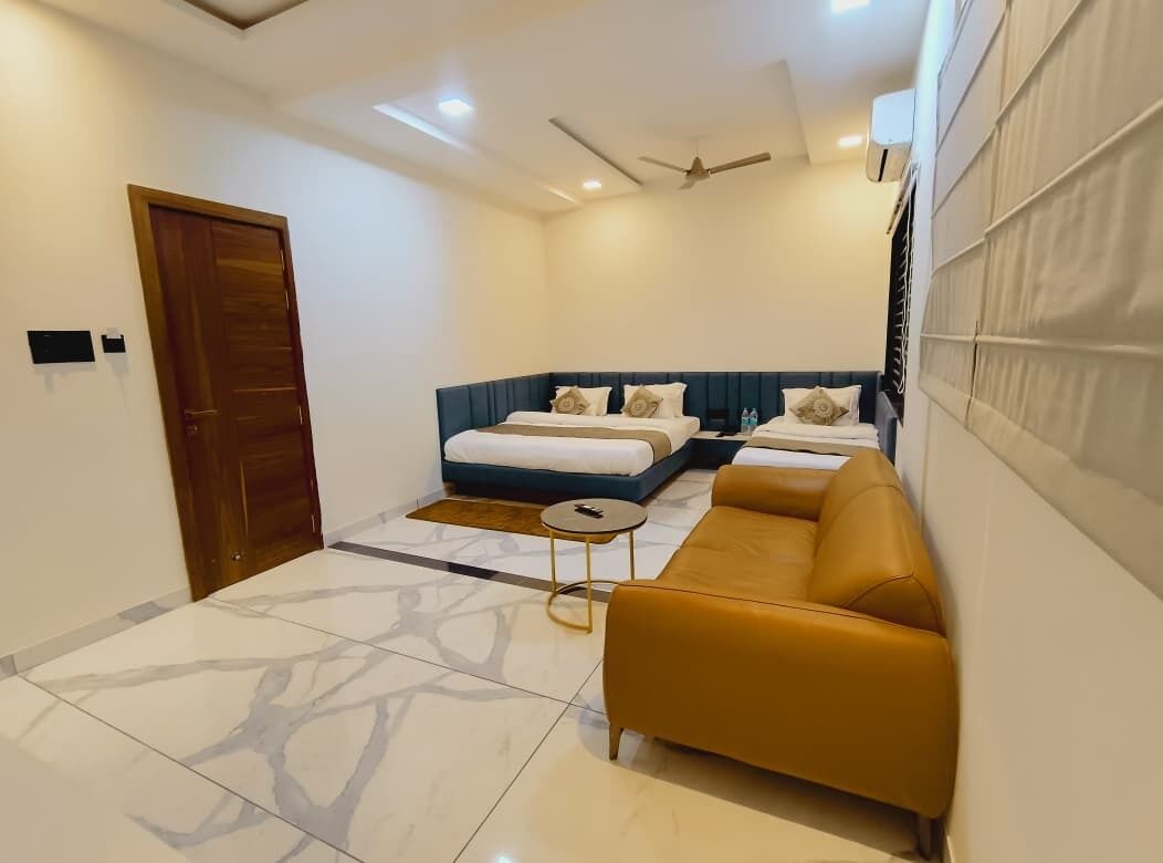 A modern hotel room with a bed, sofa, and a small table.