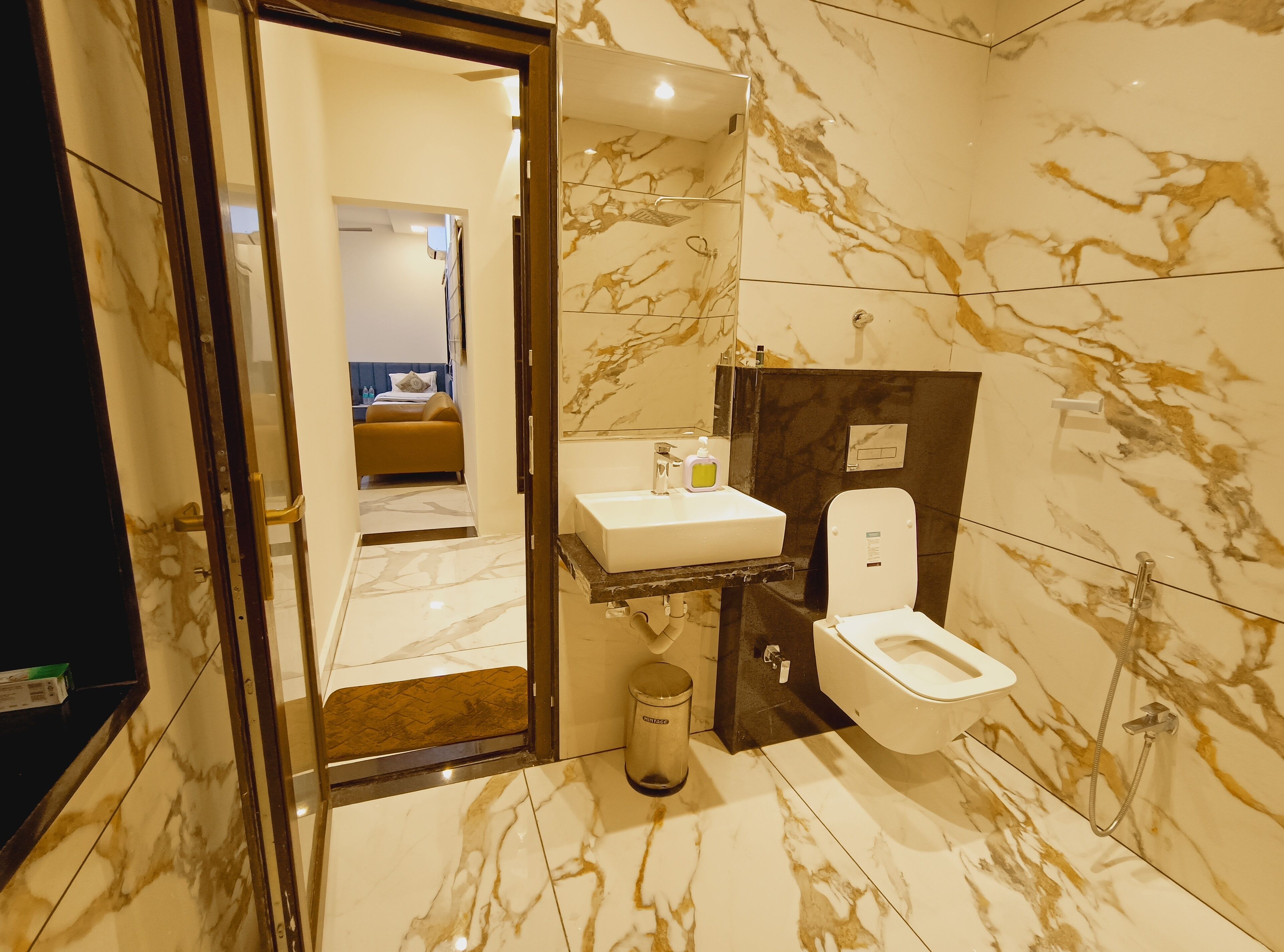 A modern bathroom with a marble floor, a white sink, a toilet, and a shower.