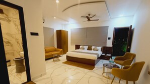 Ein modernes Hotelzimmer mit einem großen Bett, einer Couch, einem kleinen Tisch und einem Fernseher.