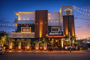 A hotel with a modern design, featuring a prominent entrance, outdoor seating, and string lights. - Hotel Nidhi Shree (Ujjain)