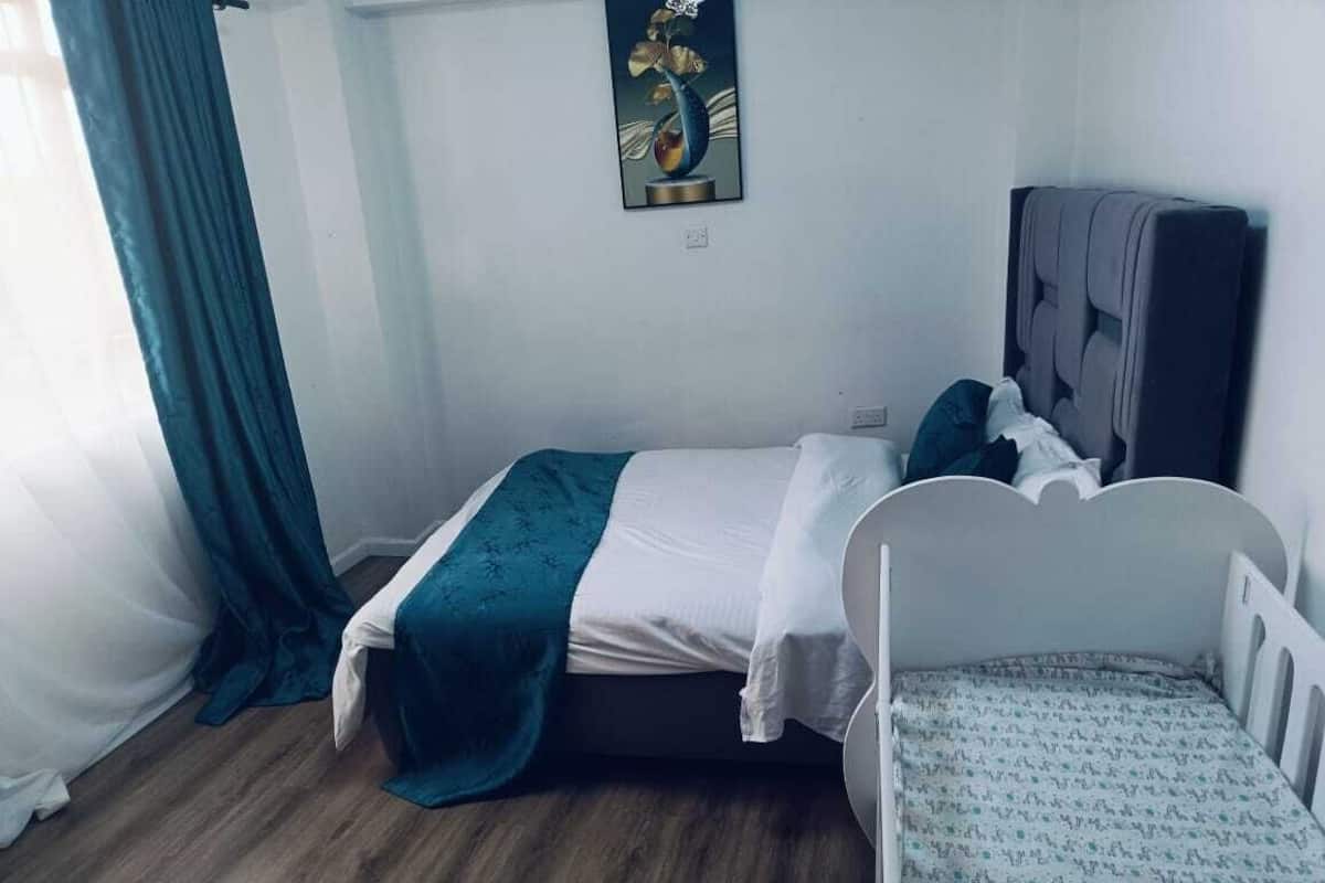 A small, neatly arranged bedroom with a single bed, a crib, and a wall-mounted artwork.