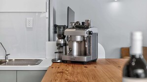 Eine Küche mit Kaffeemaschine auf einer Holzausziehtischplatte, einem Spülbecken und einer Weinflasche.