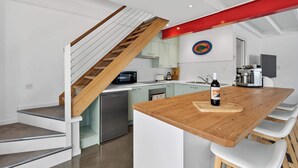 Eine moderne Küche mit einer Holztreppe, weißen Schränken und einer roten Akzentwand.